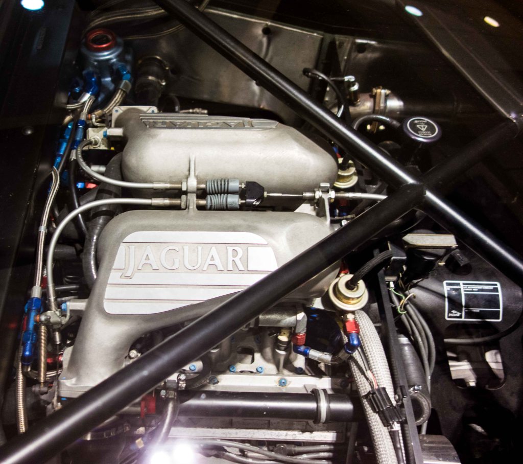 The engine is visible under a glass lid in the middle of the automobile.