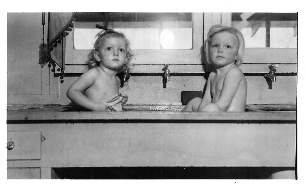 Gail and her sister Susan getting a bath in the kitchen sink.