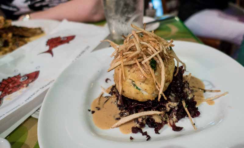 A huge crab cake on red cabbage.